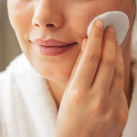 "A woman applying sunscreen on her cheek"