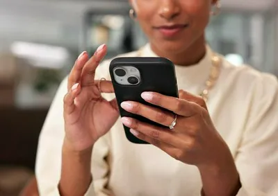 Woman scrolling on her phone, engaged with celebrity news.