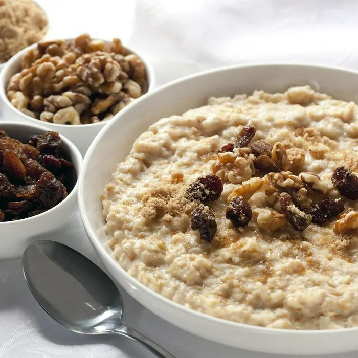 "Bowl of oatmeal with raisins, nuts, and brown sugar"