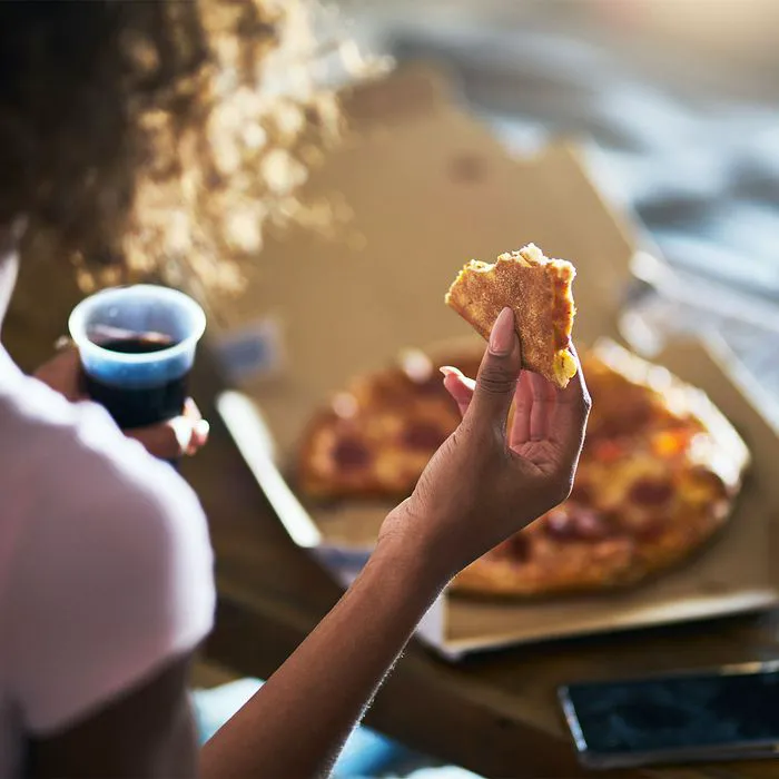 "Woman eating pizza in bed"