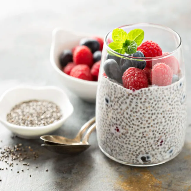 "Chia seed pudding in a glass bowl topped with fruits"
