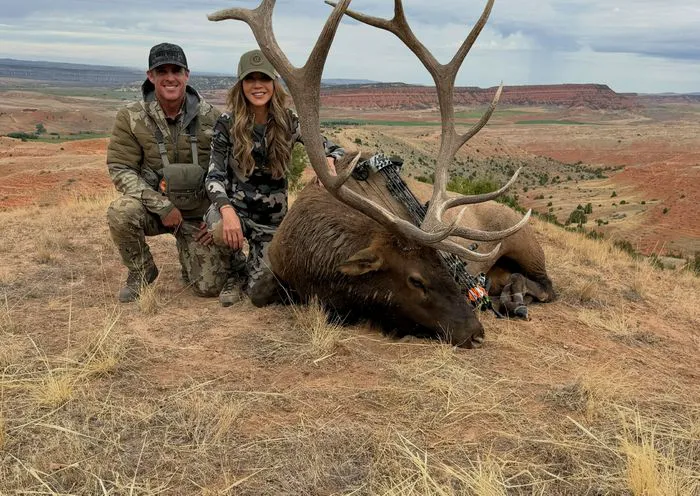Kristi Noem posing with a large elk during her hunting trip