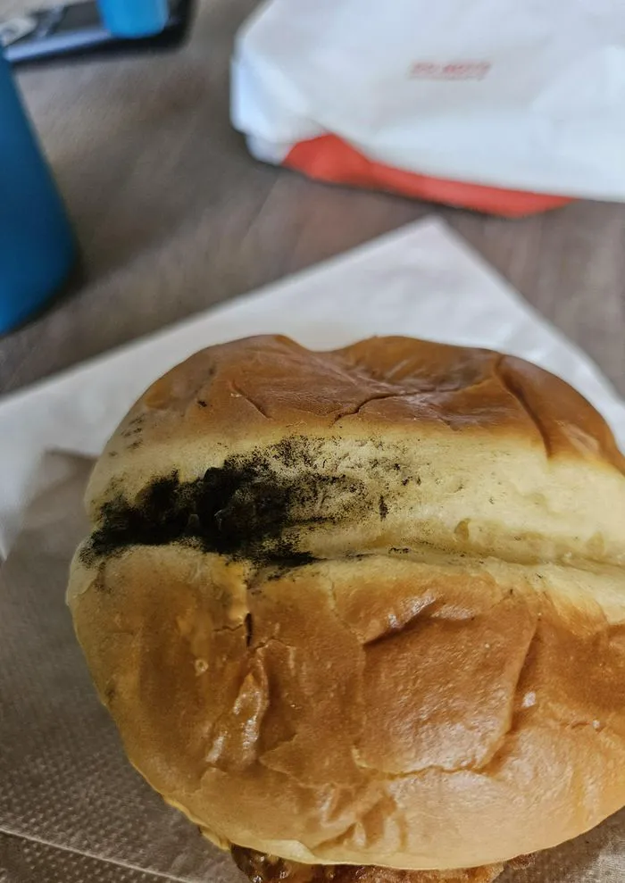 "McDonald's burger with black substance on bun"