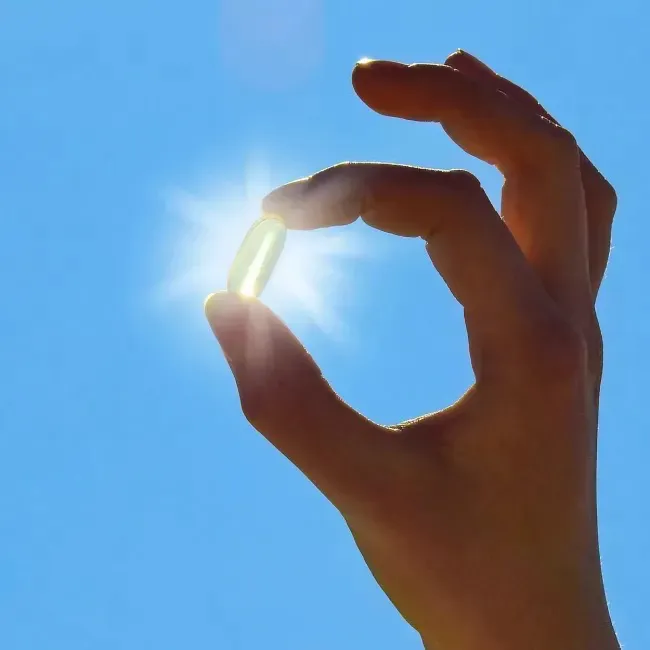 Woman holding vitamin bottle under sunlight for healthy living.